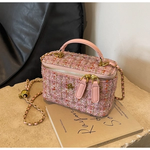 Detailed macro view of pink tweed texture with golden floral metal hardware on small bag