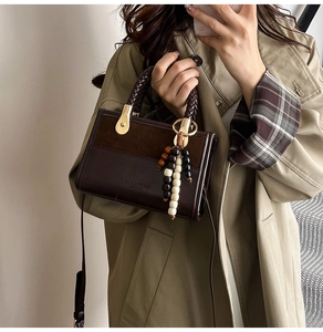 Détail du sac à main en cuir marron avec poignée tissée et pendentif en bois décoratif