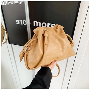 Detail of khaki leather bucket bag with drawstrings and elegant gold hardware