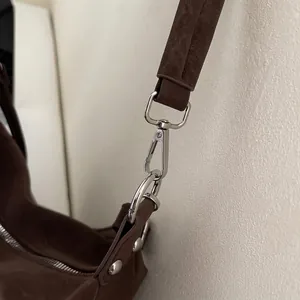 Close-up of silver metal hardware and matte brown texture on retro tote bag