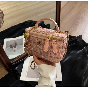 Close-up of pink tweed mini box bag with golden flower clasp and chain strap detail