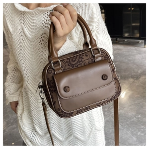 Detail of vintage brown patterned crossbody bag with double handles and front flap pocket