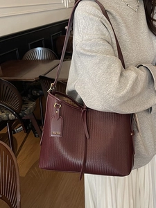 Grande borsa tote bordeaux con trama intrecciata e dettagli dorati su una modella