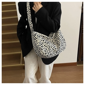 Model wearing a stylish leopard print tote bag featuring a wide shoulder strap design