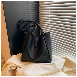 Détail d'un sac cabas minimaliste en cuir noir avec fermeture à boucle et bandoulière fine
