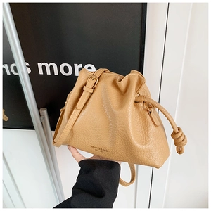 Detail of tan bucket bag showing litchi grain leather texture and adjustable strap