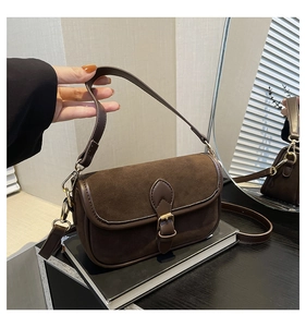 Detail of dark brown vintage saddle bag with matte suede texture and gold hardware
