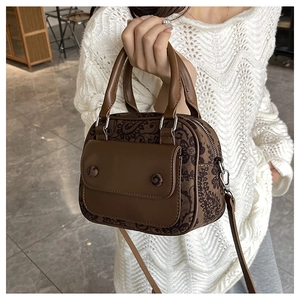 Detailed view of paisley pattern crossbody bag with brown leather trim and silver zipper