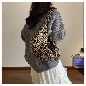 Detail of leopard print hobo bag showing pleated strap and draping effect on model