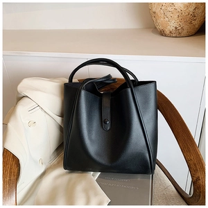 Détail d'un grand sac cabas noir en cuir avec fermeture à pression sur une chaise