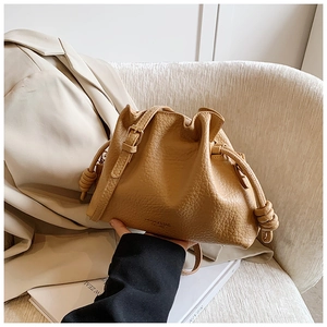 Detailed close-up of camel-colored drawstring bucket bag with lychee grain texture