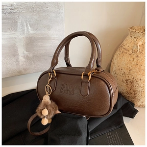 Detail view of dark brown retro bowling bag with embossed logo and fuzzy pompom charm