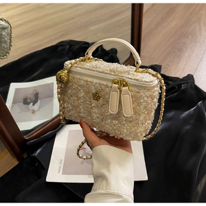 Detailed shot of tweed chain bag featuring a gold metal camellia and crossbody strap
