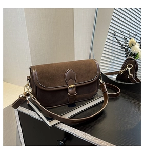 Macro detail of brown vintage crossbody bag with suede stitching and metallic buckle