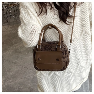 Close-up of vintage brown crossbody bag with paisley pattern fabric on a white model outfit