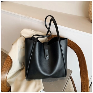Sac cabas noir mat minimaliste à fines bandoulières posé sur une chaise en bois