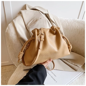 Detail of beige pleated cloud bag showing pebbled leather texture and side knot design