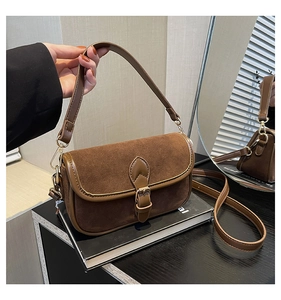Detail of vintage brown suede shoulder bag with polished gold buckle and adjustable strap
