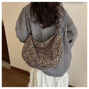 Detail of hobo shoulder bag featuring leopard print and pleated strap on model