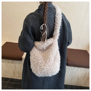 Detailed view of plush beige teddy fleece crossbody bag worn with a dark winter coat