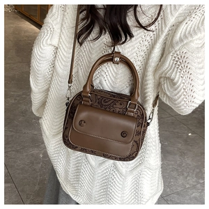 Close-up of brown paisley crossbody bag with a solid front pocket and top handles