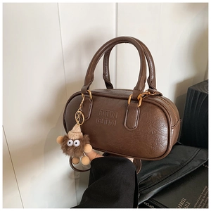 Detail of vintage coffee brown bowling bag featuring embossed ATN logo and plush charm
