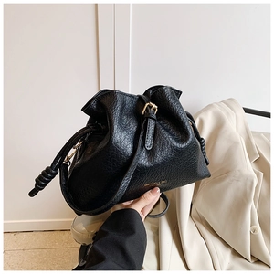 Detail of black drawstring bucket bag with litchi texture and gold logo lettering