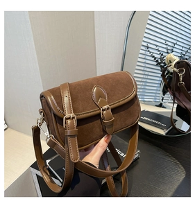 Detail shot of vintage brown satchel featuring suede texture and decorative buckles