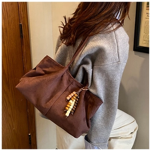 Détail d'un sac à bandoulière en daim café noir avec des glands décoratifs en bois