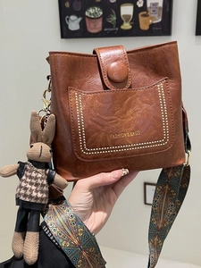 Vintage brown leather bucket bag with star rivets and a plaid bunny charm pendant