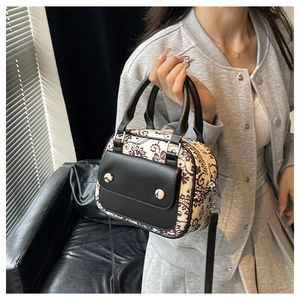 Detail view of floral vintage crossbody bag with a black leather front pocket and strap