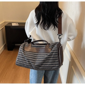 Detail of grey striped canvas travel bag with premium brown leather trim and shoulder strap