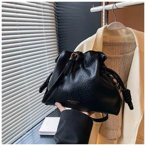 Detail of black drawstring bucket bag with textured leather and gold MIKAXXI logo