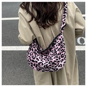 Street style shot of a hot pink leopard print crossbody tote bag on a wide strap