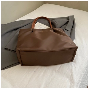Detail of coffee brown tote bag with leather handle and golden magnetic closure