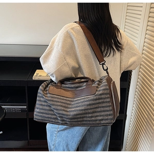 Detail of retro striped gym bag featuring brown leather trim and nice bag embossed logo