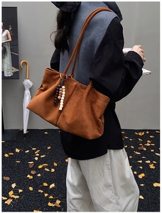 Vue détaillée d'un sac cabas en daim marron avec une breloque décorative en perles unique