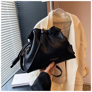 Close-up of black lychee grain leather bucket bag with gold buckle and stylish pleats