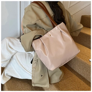 Detail of light pink tote bag with pleated texture, brown straps and gold magnetic snap