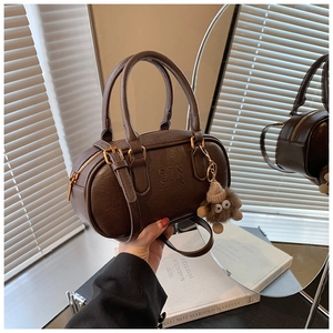 Detail of dark brown vintage bowling bag with logo embossing and plush charm accessory