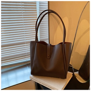 Détail d'un grand cabas marron foncé avec texture en cuir mat et longues bandoulières