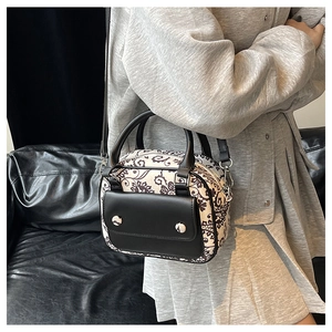 Detail of a black and white floral pattern canvas crossbody bag with silver studs