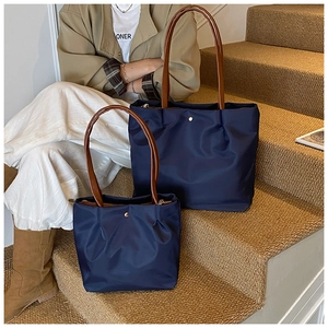 Detail of navy blue tote bags in two sizes with gold snap buttons and leather straps