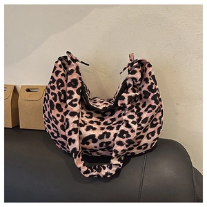Detail view of pink and black leopard print tote bag with ruched strap on black sofa