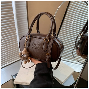 Detail of dark brown vintage Boston bag with ATN embossed logo and plush toy charm