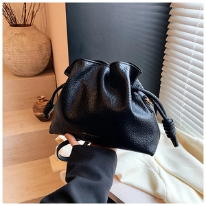 Detail of black drawstring cloud bag with lychee pattern leather and gold logo