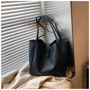 Détail d'un sac cabas en cuir noir minimaliste avec fine bandoulière et boucle