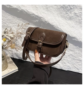 Close-up of vintage brown suede shoulder bag showing metal buckle and matte texture