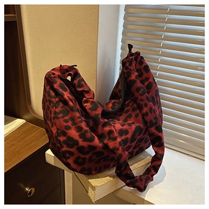 Detail of red and black leopard print hobo bag with knotted shoulder strap and zipper