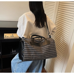 Detail of grey striped travel duffel bag with leather trim and adjustable shoulder strap
